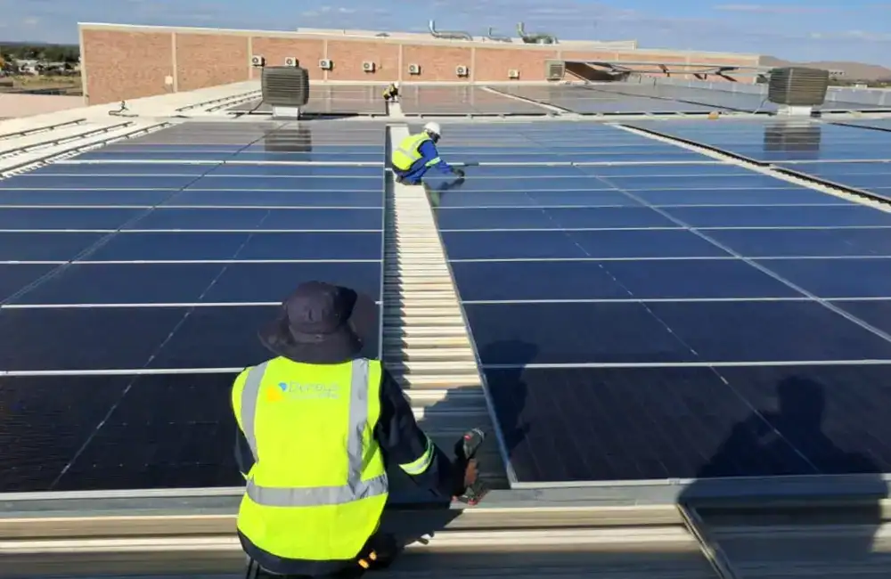 Technician working on a large commercial rooftop solar installation in the UK under harsh sunlight conditions